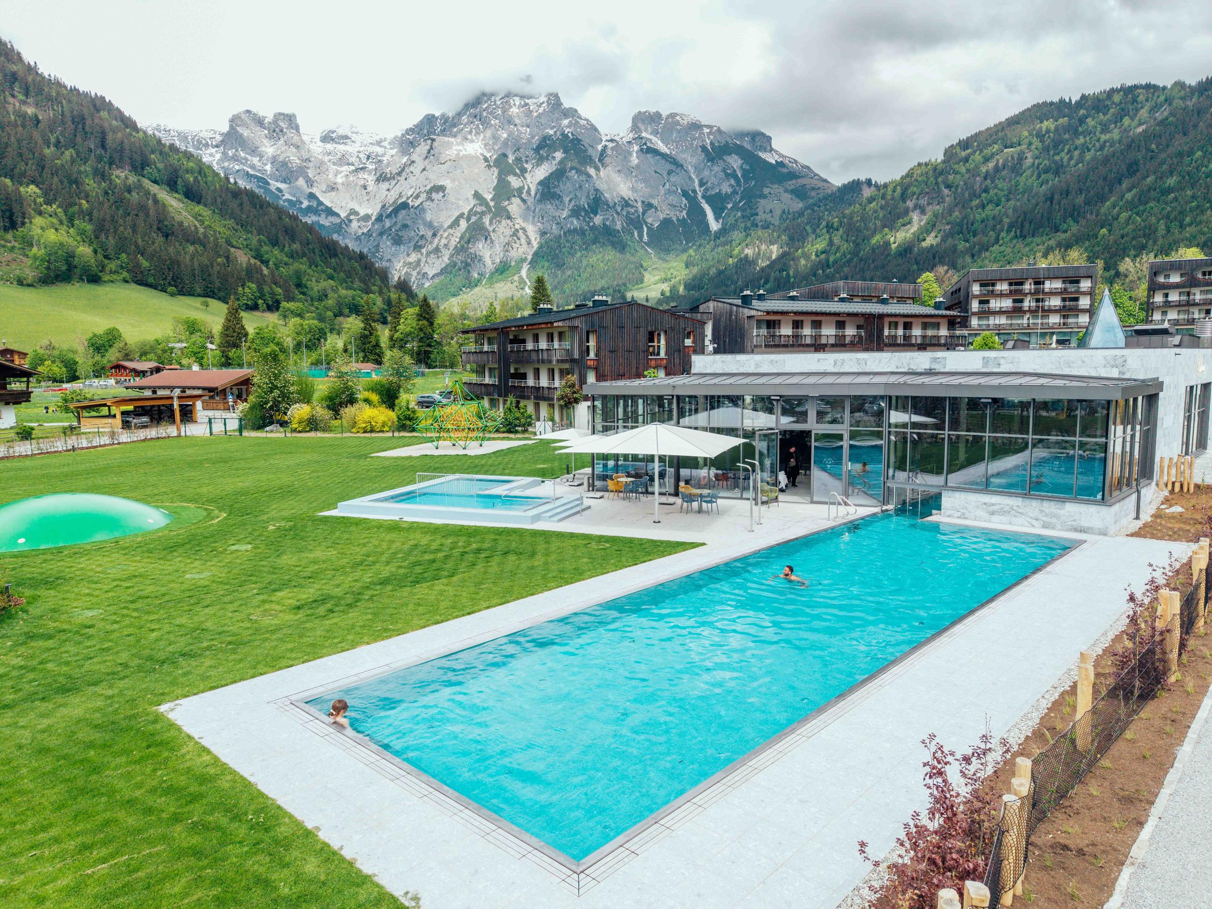 Außenpool und Spa des Bergresorts Werfenweng vor alpiner Bergkulisse